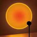 Lampe noire projetant un cercle de lumière orangée sur un mur.