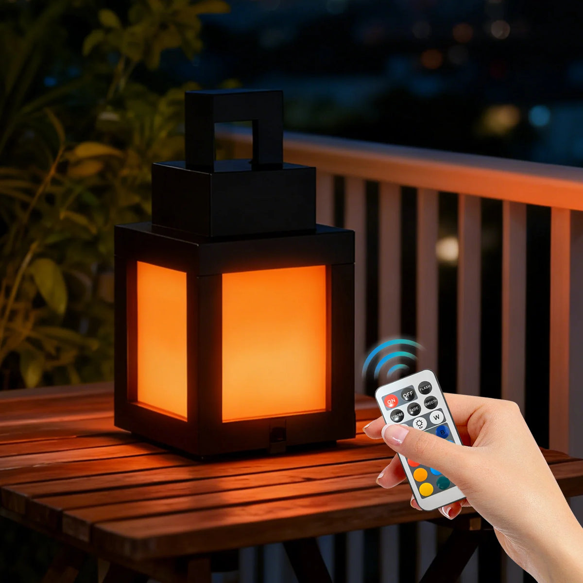 Lanterne Pixelia Mini allumée sur une table extérieure, avec une main tenant une télécommande.