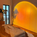 Grande projection lumineuse orangée sur une armoire, avec l’ombre d’une plante.