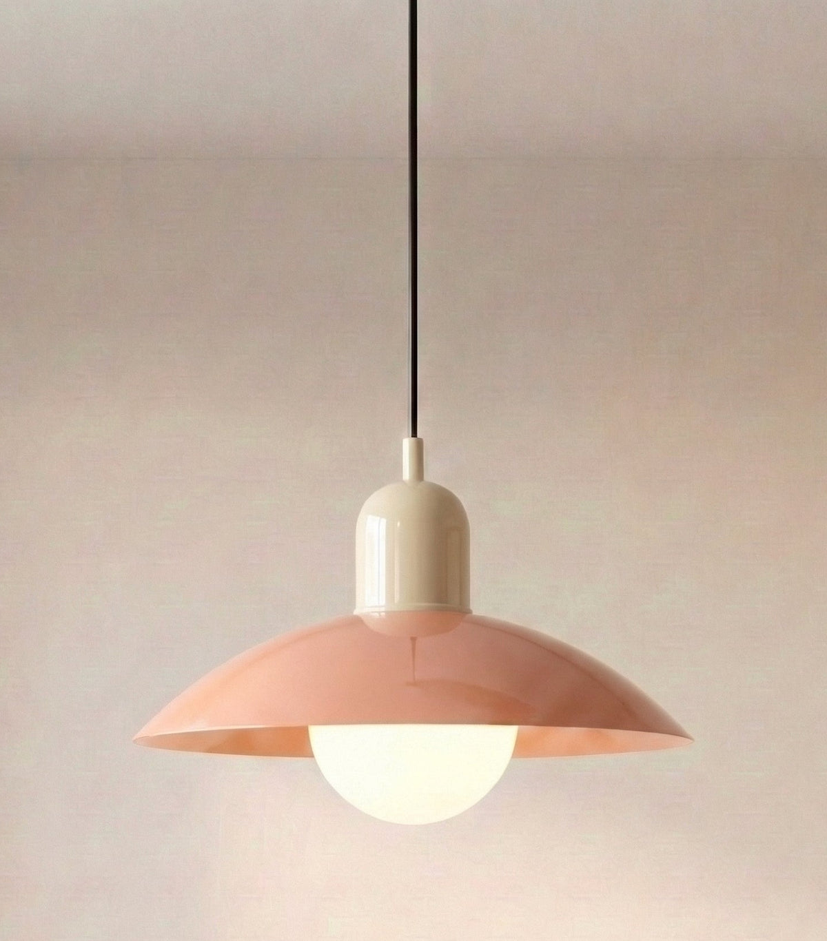 Caléria, abat-jour rose et col clair, avec câble noir et globe lumineux.