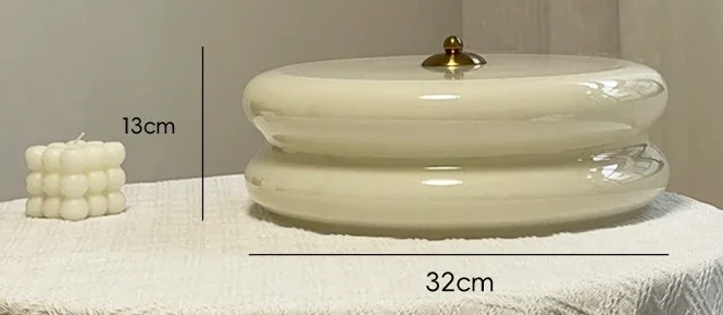 Photo fournisseur de Ciselé beige posé sur une table, avec repères de diamètre 32 cm et hauteur 13 cm.