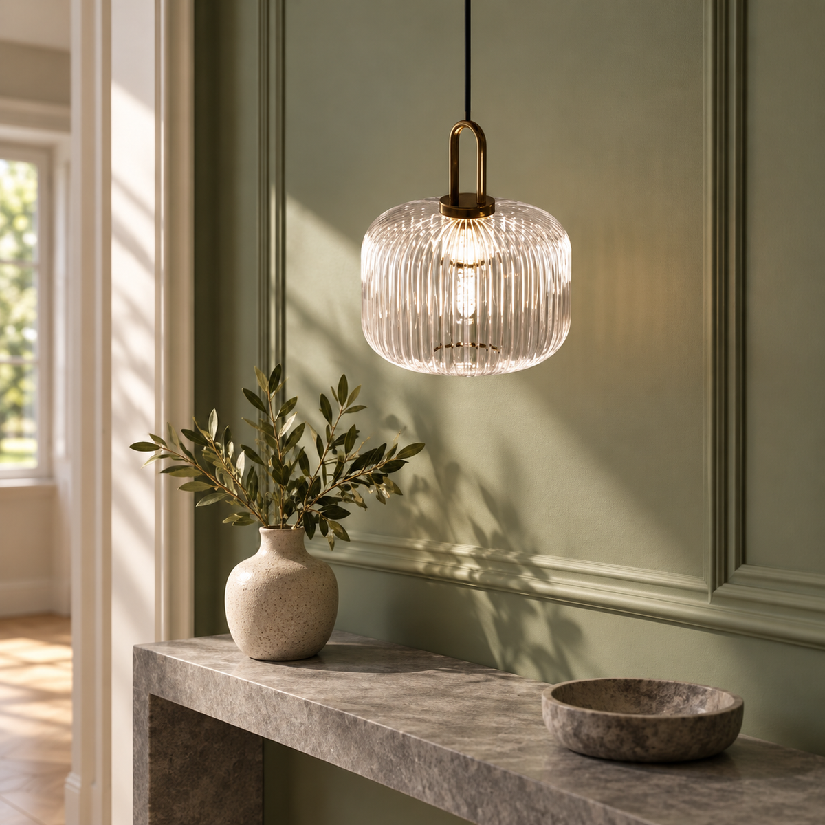Suspension en verre côtelé dans un décor illustratif au-dessus d'une étroite console de pierre grise dans un couloir aux murs vert sauge et moulures sobres