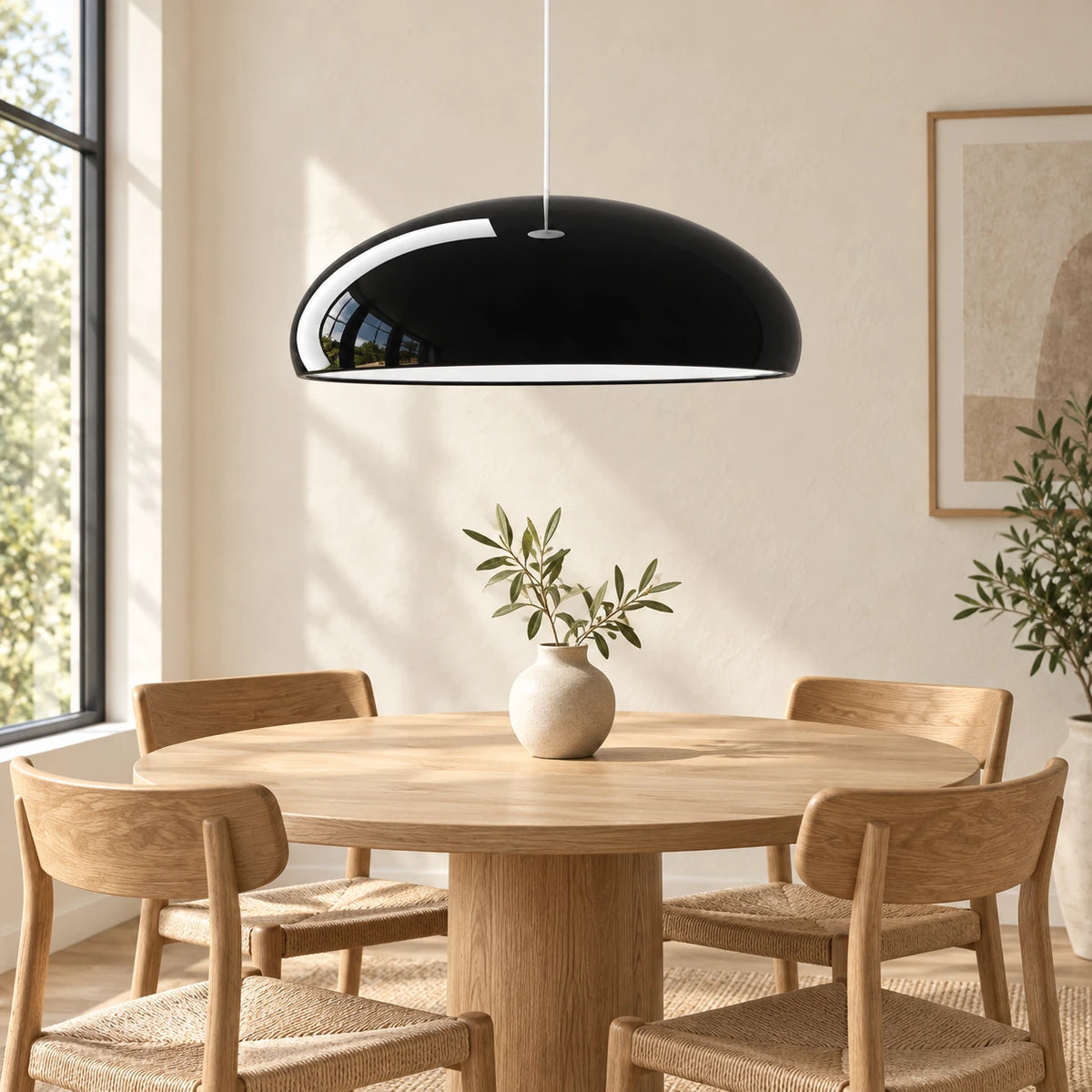 Suspension dôme noire au-dessus d’une table ronde en bois clair.