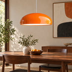 Suspension dôme orange au-dessus d’une table en noyer.