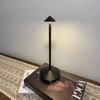 Élancée — lampe noire à longue tige et petit abat-jour conique, posée sur un livre