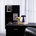 Galet — lampes dorée et noire à abat-jour arrondi et pied conique, disposées sur un bureau