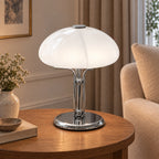 Girolle — lampe à dôme blanc et pied chromé, sur une table près d’un fauteuil clair — mise en scène illustrative