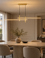 Suspension Linéva Or Champagne allumée au-dessus d’une table, dans une salle à manger chaleureuse.