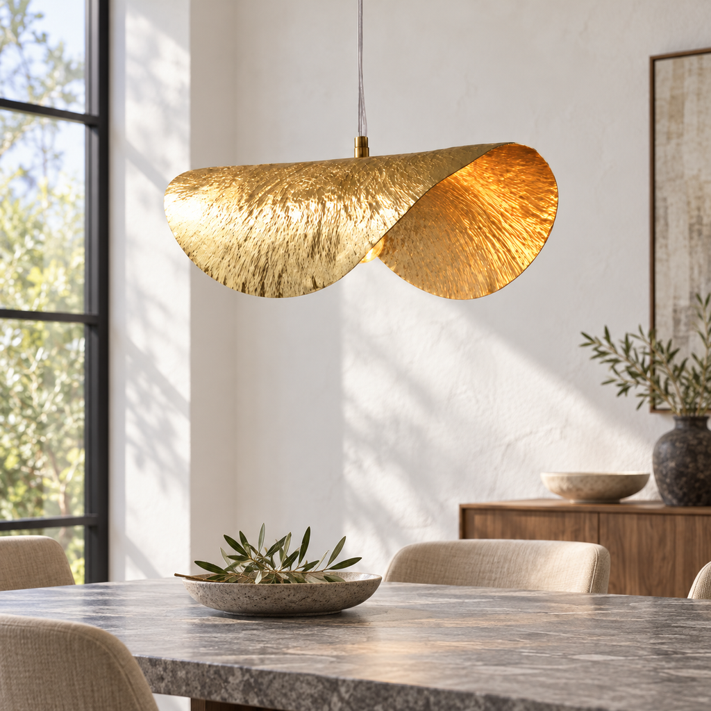 Suspension feuille de lotus dorée dans un décor illustratif au-dessus d'une table de repas rectangulaire en pierre grise dans une pièce avec mur enduit blanc et grande fenêtre à encadrement noir