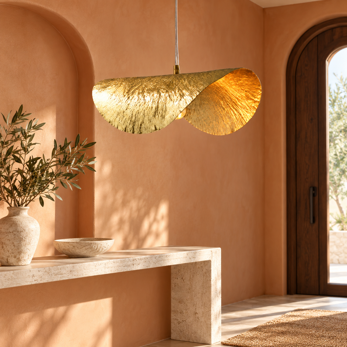 Suspension feuille de lotus dorée dans un décor illustratif dans une entrée avec mur terracotta pâle et niche cintrée