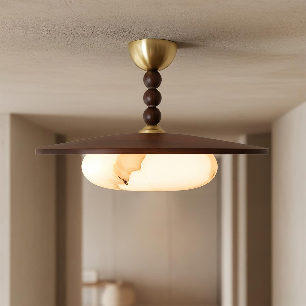 Plafonnier Bosquet allumé, vu de face dans un couloir, avec disque en bois foncé et trois sphères décoratives.