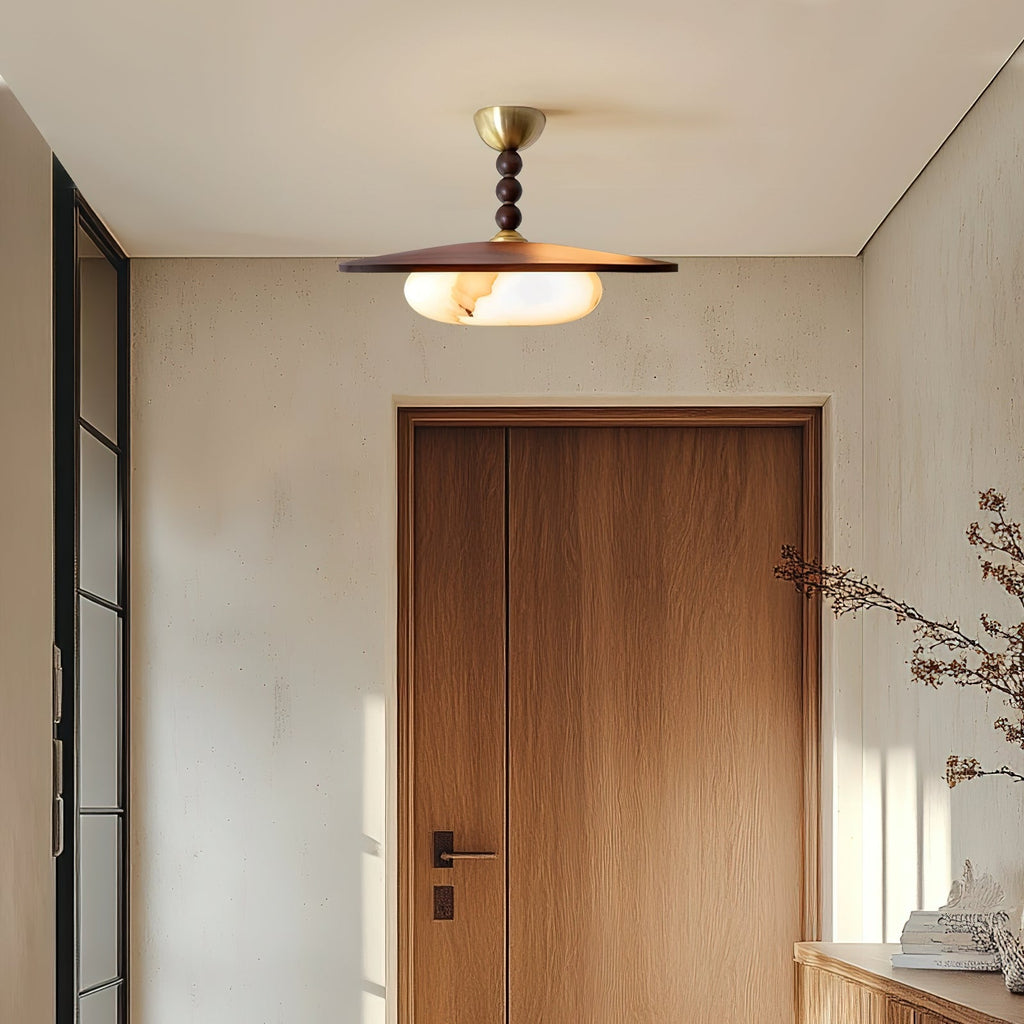 Plafonnier Bosquet allumé au plafond d’une entrée beige avec porte en bois, vue générale de l’installation.