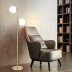 Gémelle, lampadaire doré à deux globes blancs — Coin lecture avec bibliothèque