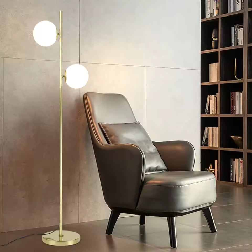 Gémelle, lampadaire doré à deux globes blancs — Coin lecture avec bibliothèque